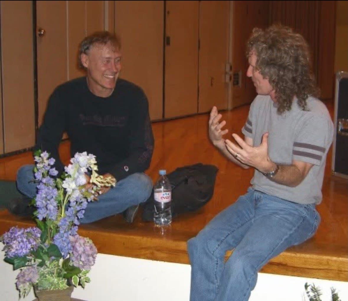 Bruce Hornsby (left) in conversation with Steve Rucker, both seated on the edge of a stage